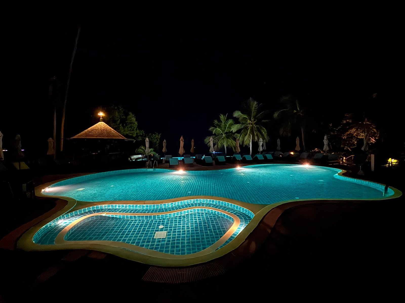 Coral Cliff Beach Resort pool illuminated at night with sea views