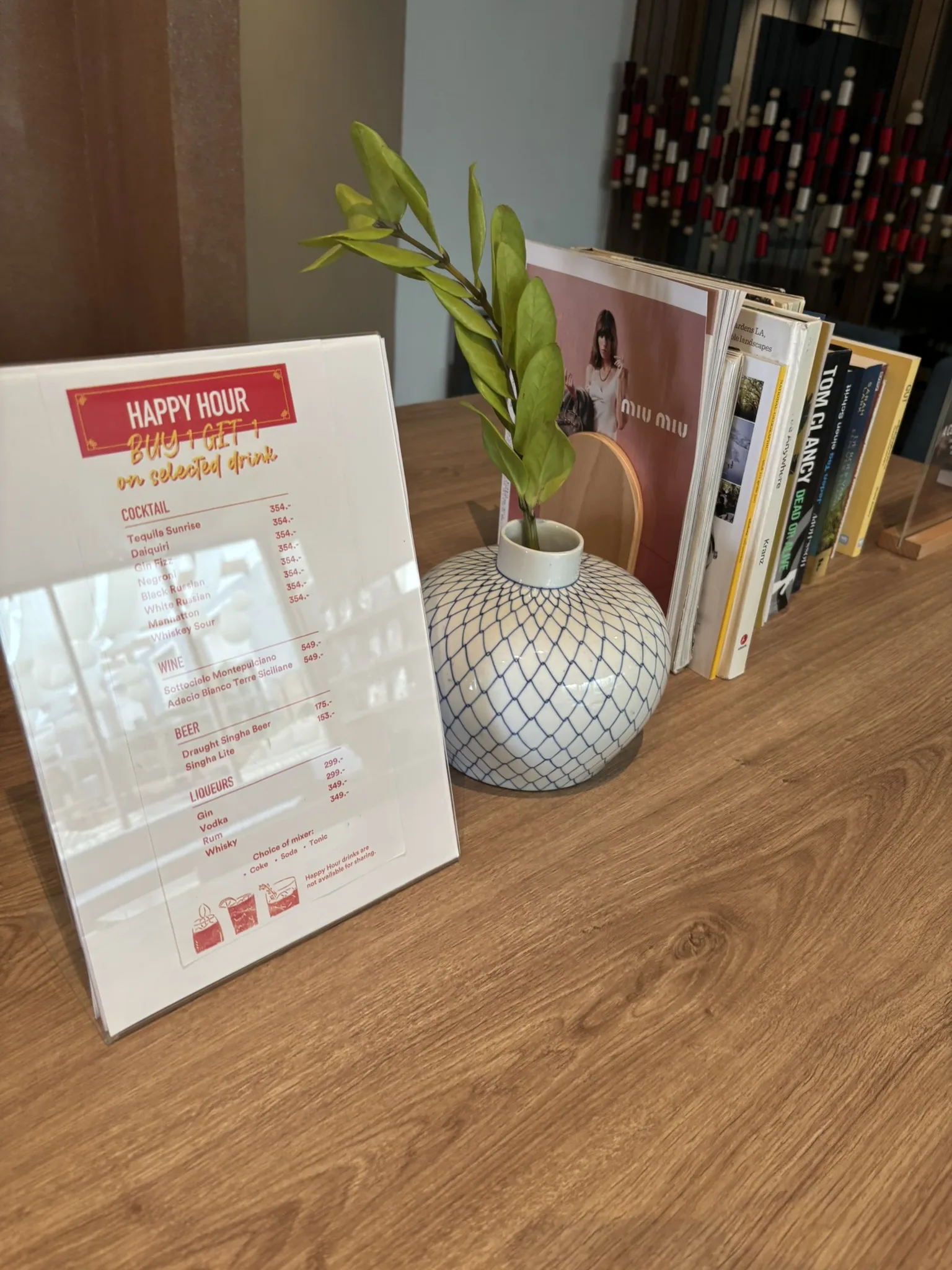 Happy hour buy-one-get-one menu card on a table at the bar of ASAI Bangkok Chinatown