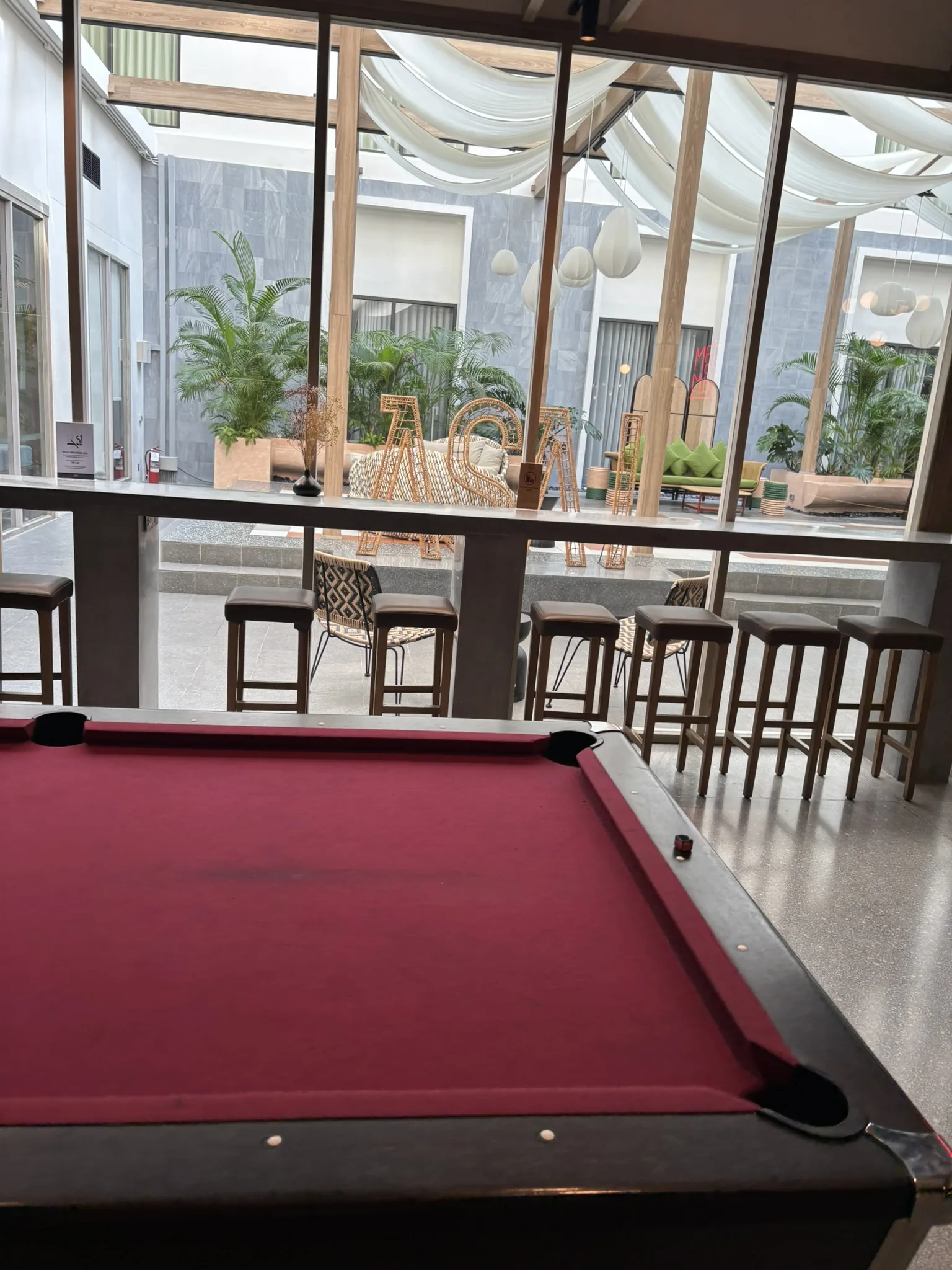Red pool table in the games area with a view of the outdoor terrace at ASAI Bangkok Chinatown