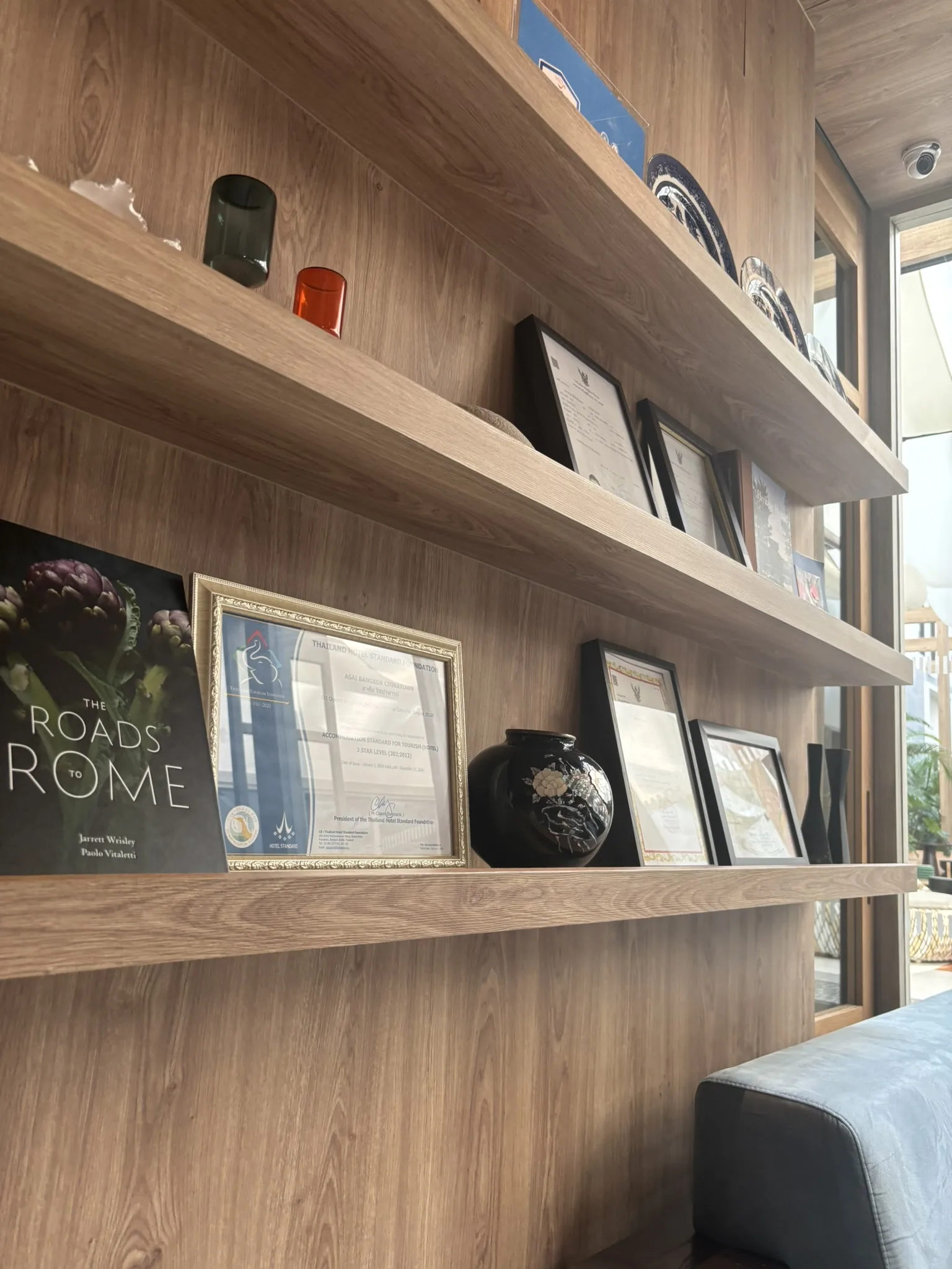 Wooden bookshelf display with framed awards and decorative objects in the lobby of ASAI Bangkok Chinatown