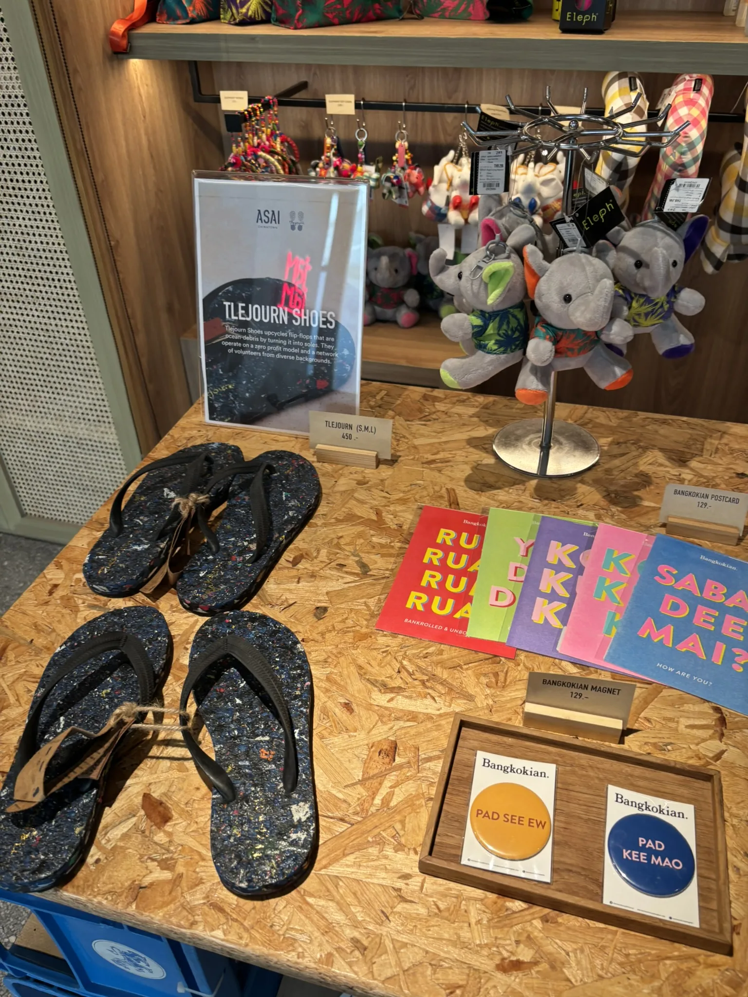 Hotel shop shelf with Tlejourn recycled flip-flops, Bangkok souvenir books, and local products at ASAI Bangkok Chinatown