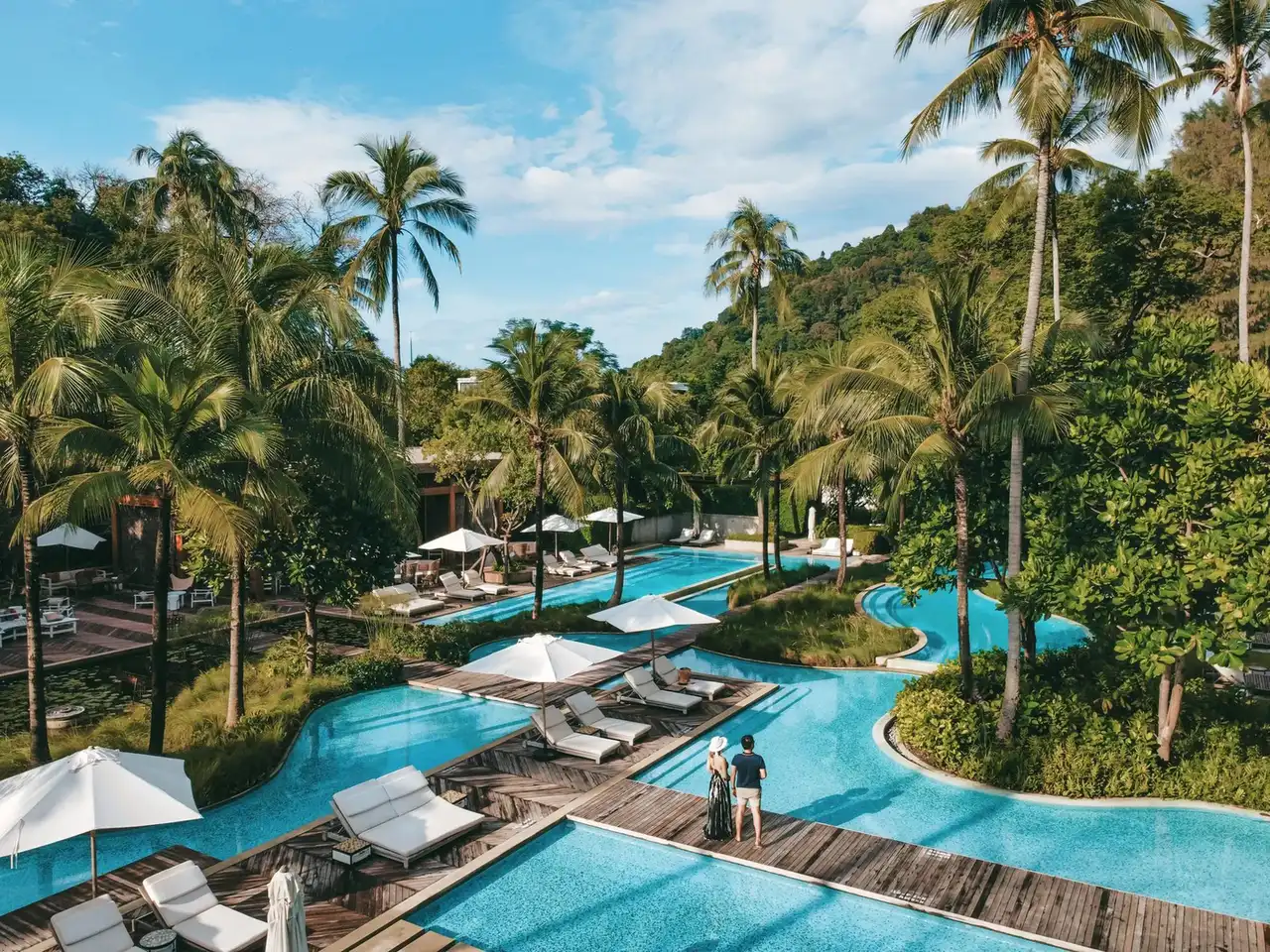 Rosewood Phuket Thailand resort pool with wooden deck bridges and tropical palms