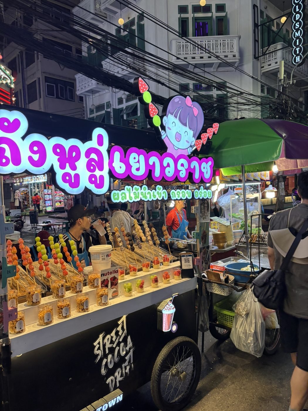Yaowarat dessert cart at night, Bangkok Chinatown, selling candied fruit skewers and sugar-coated snacks