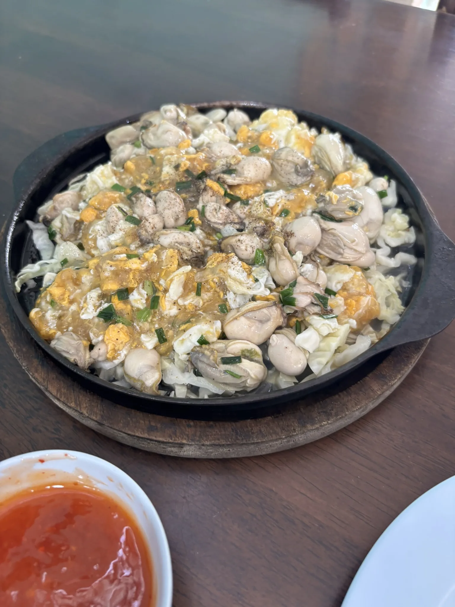 Sizzling oysters with egg on a hot plate at Chao Ruea Seafood, an affordable local Hua Hin restaurant near the fishing village